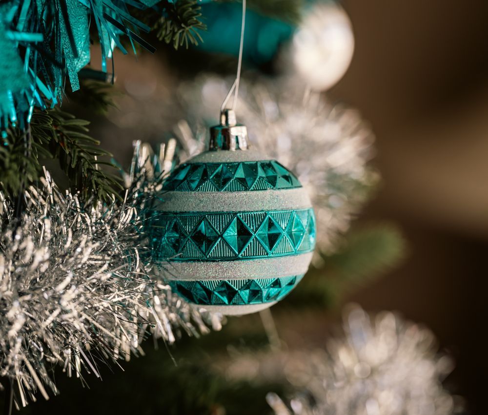 Teal glass bauble on a silver flocked Christmas tree