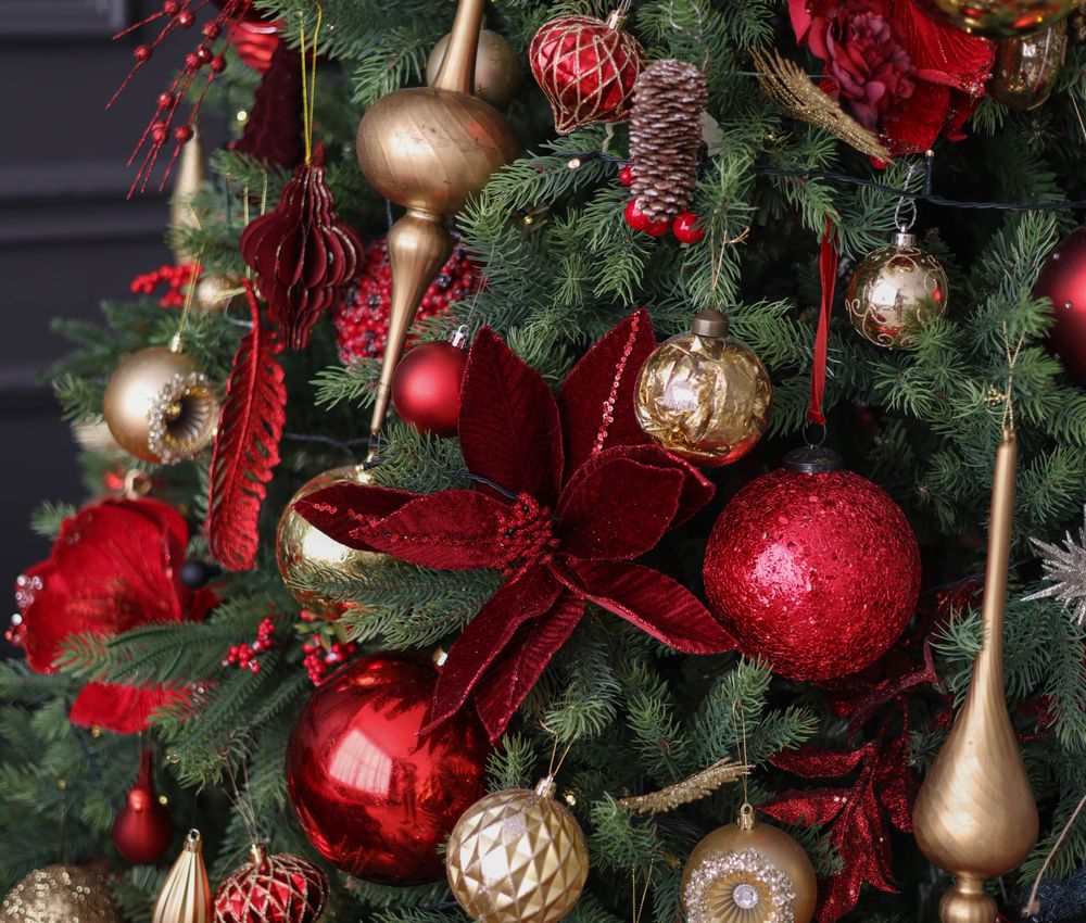 Red poinsettia and gold baubles on a green Christmas tree